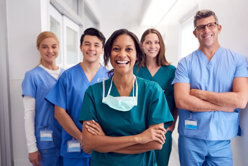 Portrait Of Laughing Multi-Cultural Medical Team Standing In Hospital Corridor