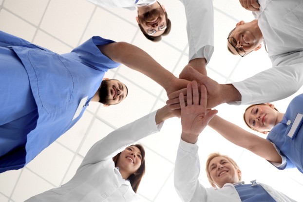 Vets standing in a circle holding out their hands in a huddle